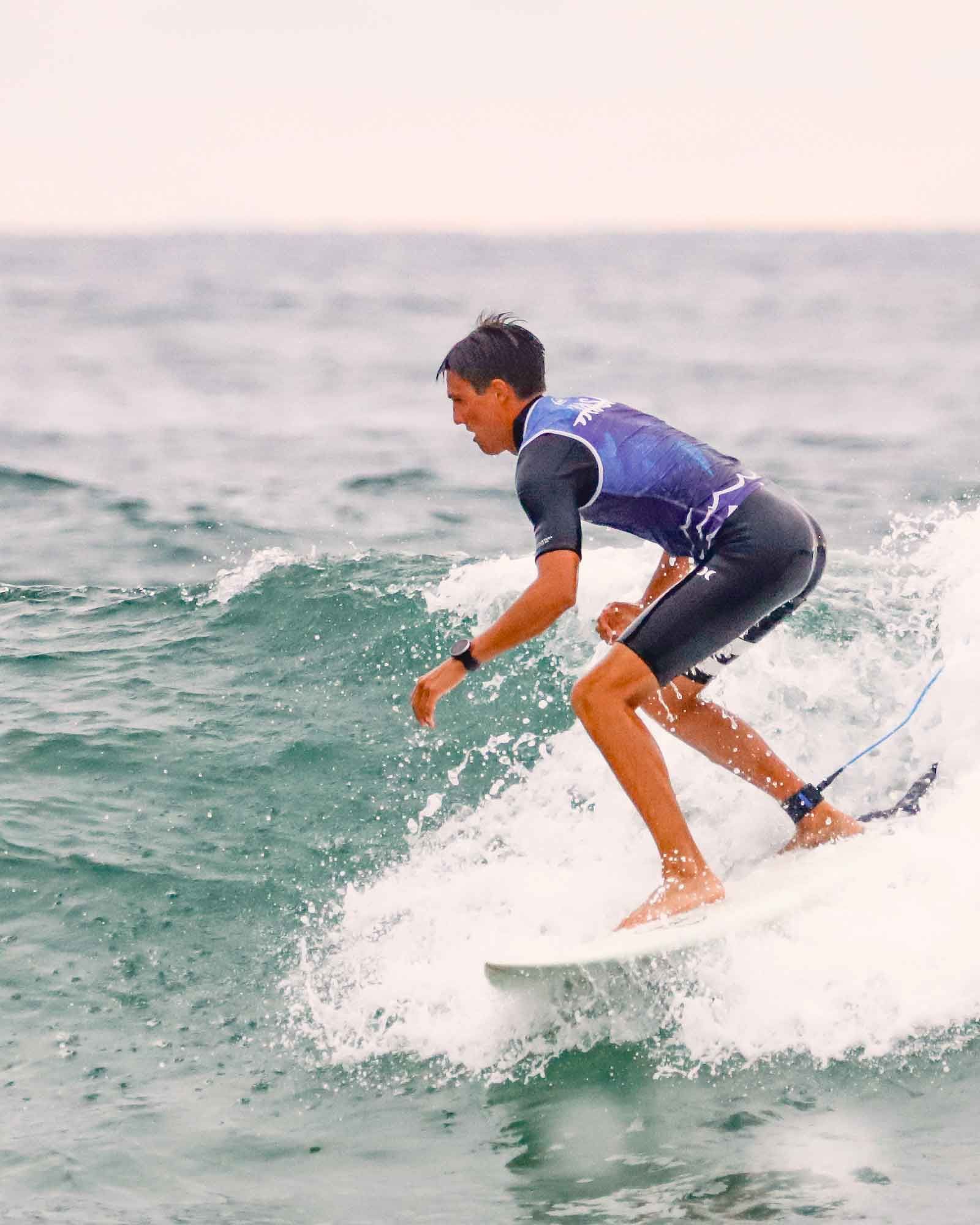 jeune adulte sur la vague en planche résine lycra bleu école de surf wasa