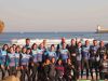 groupe de vingt personnes en combinaison de surf avec planche posant sur la plage avant un cours de surf capbreton